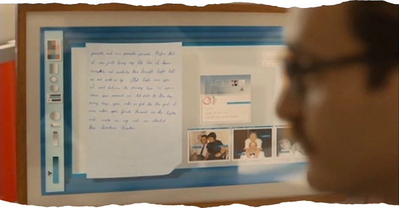 Theodore from the film 'Her', with a computer in the background that has physical beautiful things on the display, it is as if the whole screen is a piece of art, nice, warm, and lovely, and then the whole screen is framed in a wooden box, it is so beautiful and nice.